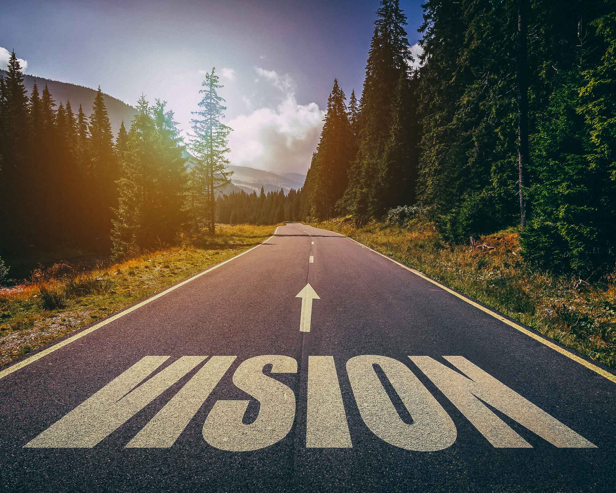 Tie, jonka asvaltissa lukee ‘VISION’ ja nuoli osoittaa eteenpäin, symboloiden strategista suuntaa ja tulevaisuuden kasvua brändäyksessä ja markkinoinnissa.